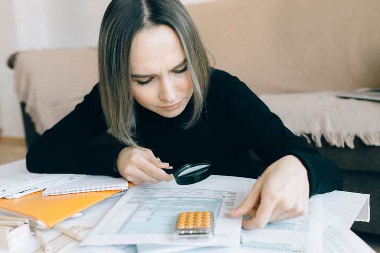 A focused young woman examines documents with a magnifying glass, auditing AI Content Strategy
