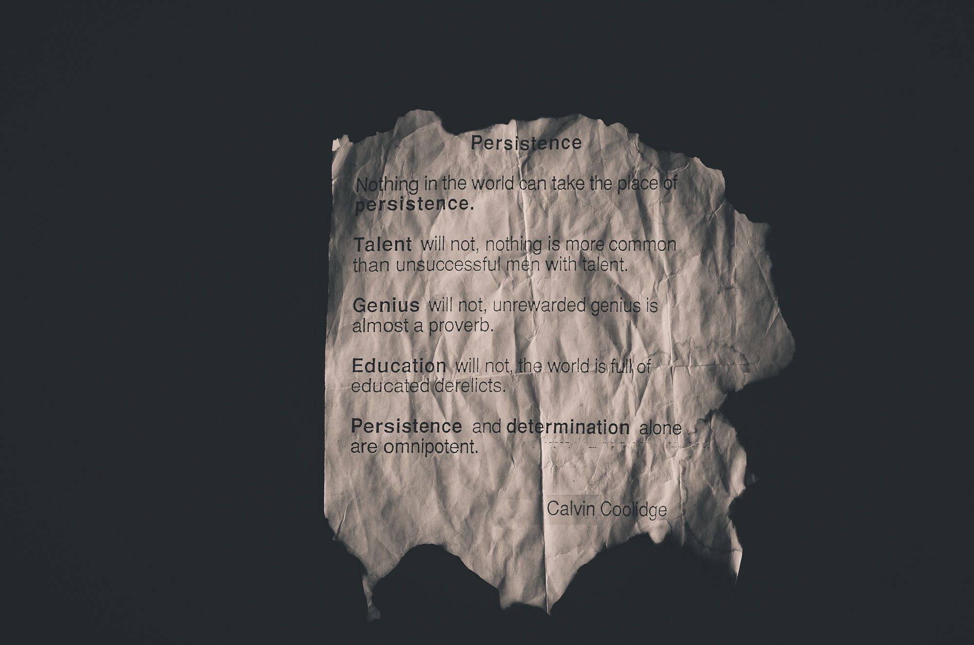 Calvin Coolidge quote on perseverance printed on crumpled paper.