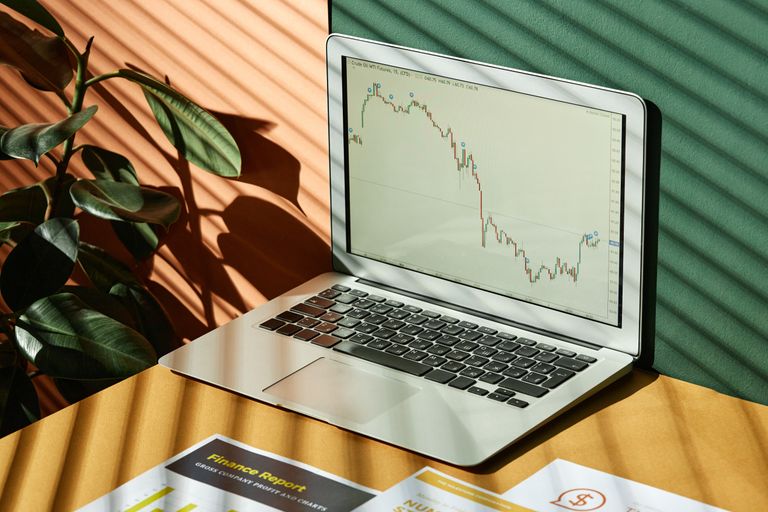 Laptop displaying a graph with reports, in a sunlit workspace.