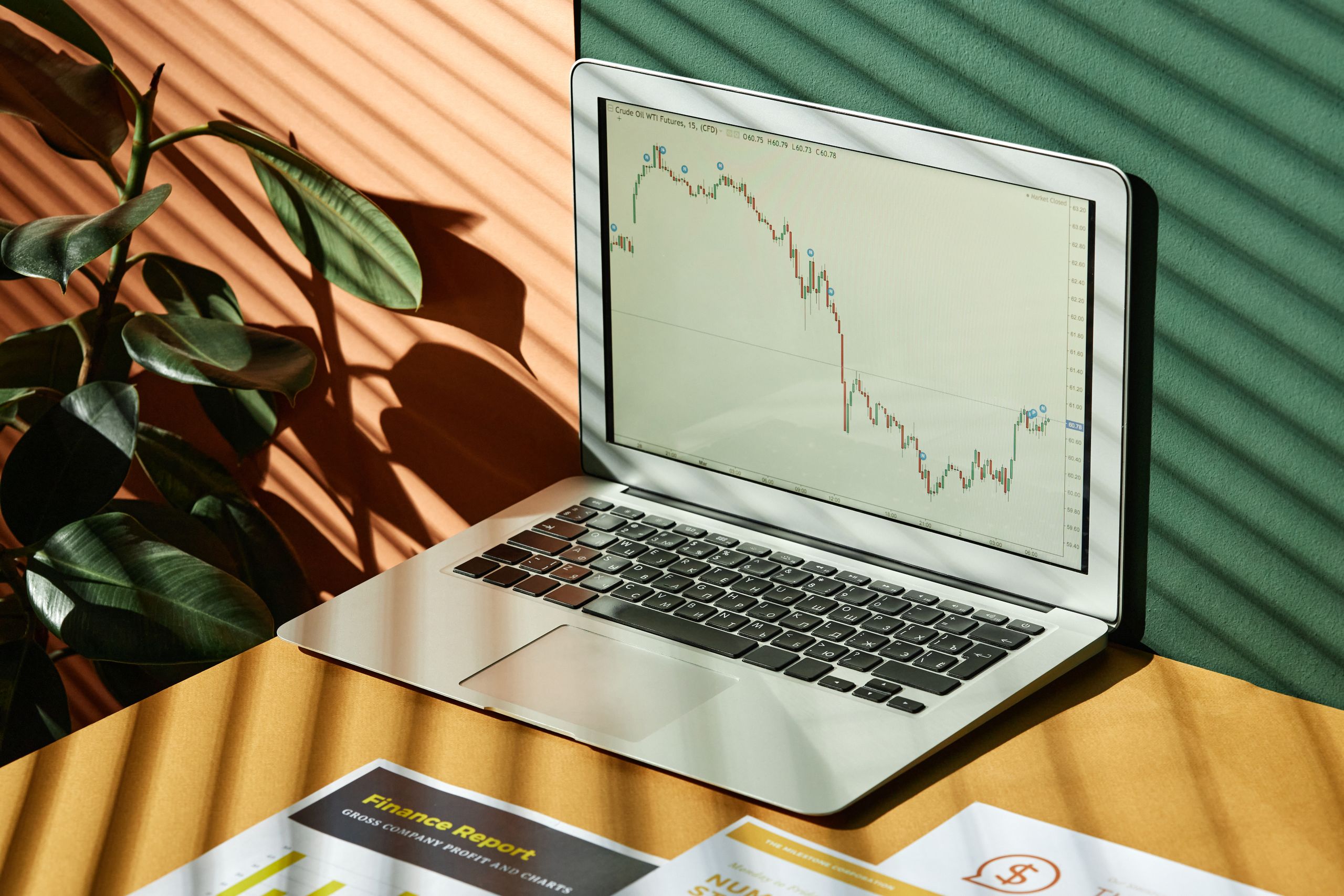 Laptop displaying a graph with reports, in a sunlit workspace.
